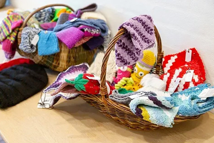 Körbe mit bunten gestrickten Artikeln.
