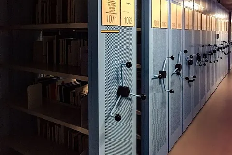 Reihen von Archivregalen in einem dunklen Raum.