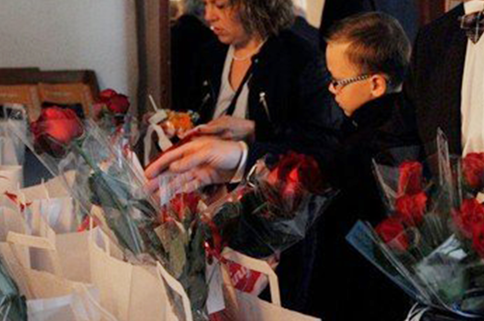 Ein Kind greift nach einer roten Rose in einem Korb voller Blumen.