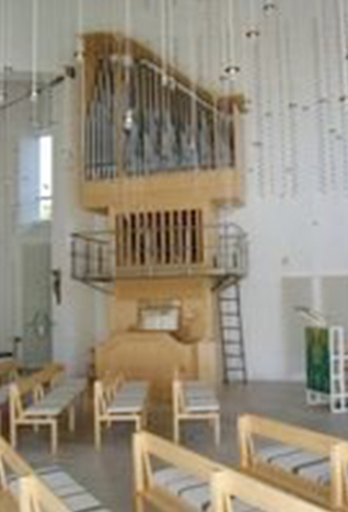 Moderner Kircheninnenraum mit Holzorgel und hellen Holzbänken.