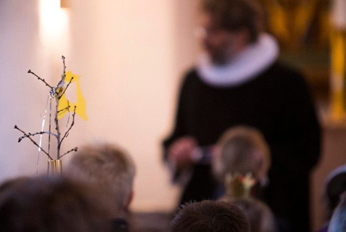 Unschärfes Bild eines Pfarrers, der vor einer Kirchengemeinde spricht.