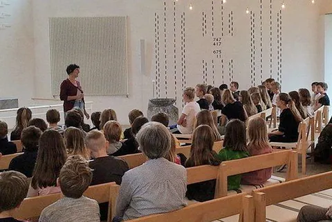 Rückansicht einer Versammlung in Kirchenbänken.